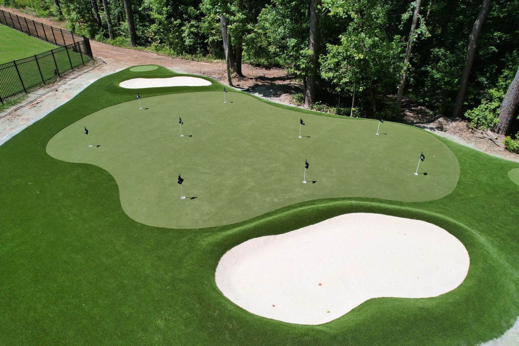 Multi-hole residential short-game academy with sand bunkers and tournament flags, built by Surface Evolution