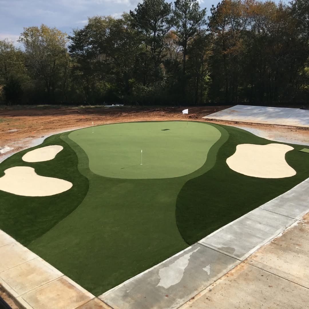 Sprawling residential short-game green with white sand bunker and backyard pool in Iowa